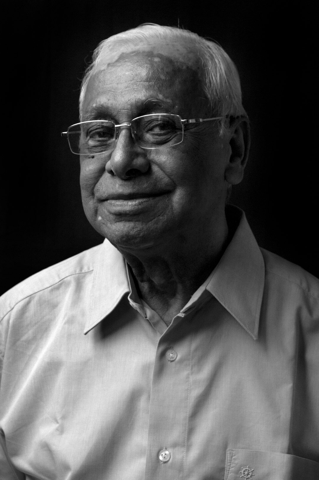 Studio portrait of a smiling older man with glasses