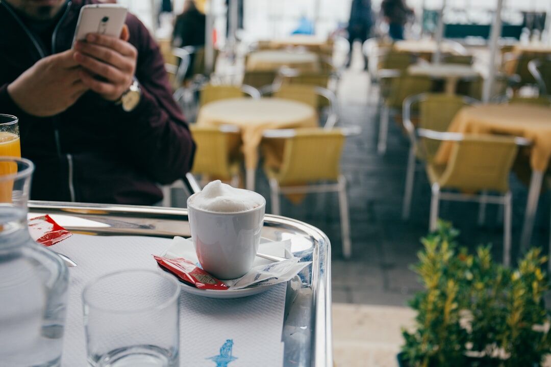Person typing a message on a smartphone at a café table